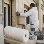 Iteiste en action posant l’ITE sur une façade en chantier